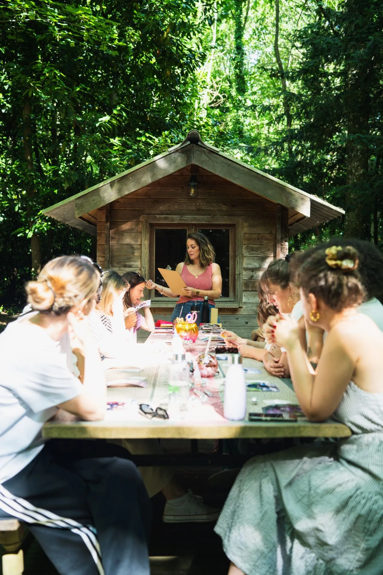 Atelier créatif sur l'image de soi, autour d'une grande table en pleine forêt, devant une cabane en bois