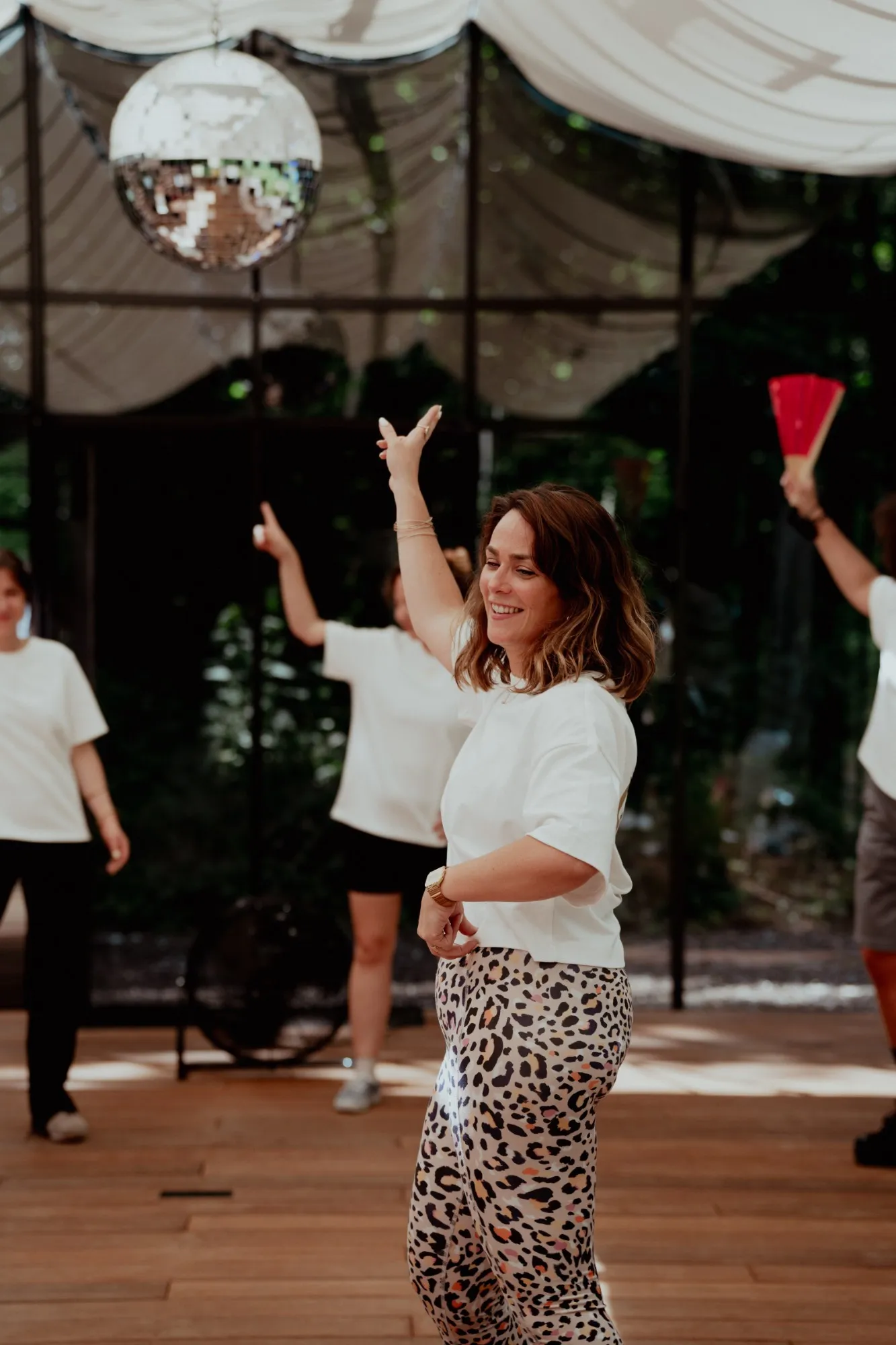 Une participante en legging léopard danse en souriant, le bras levé, sous la boule à facettes