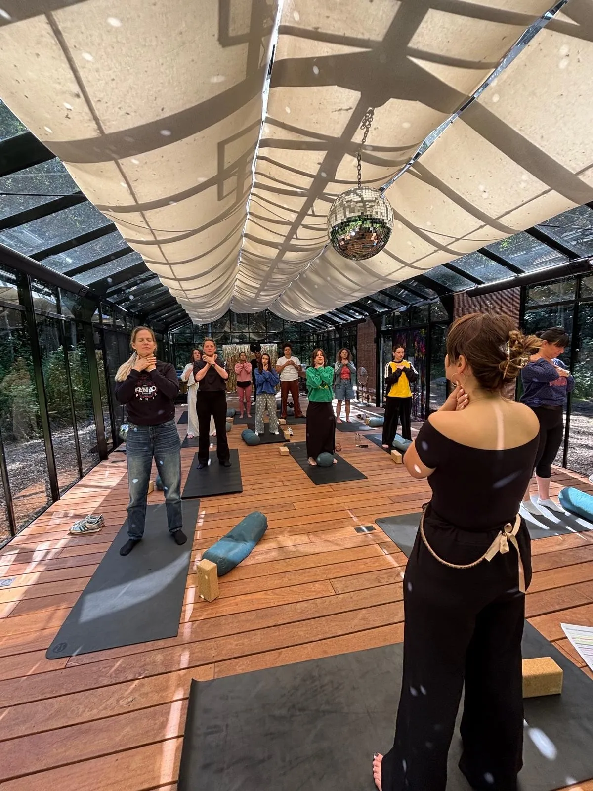 Yoga vocal sous la verrière : les participantes, debout sur leurs tapis, posent les mains sur leur gorge, sous la boule à facettes